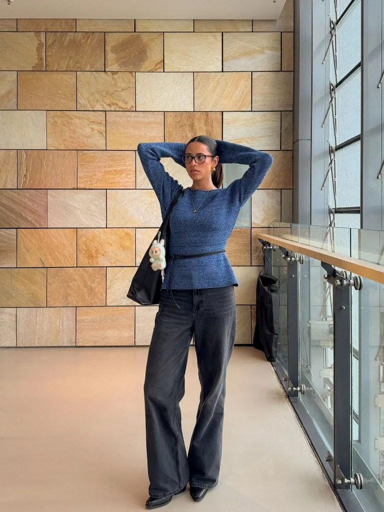 Blue fitted knit sweater with dark wide-leg jeans and black tote