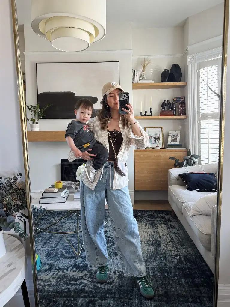 Mirror selfie holding toddler in striped shirt and barrel jeans