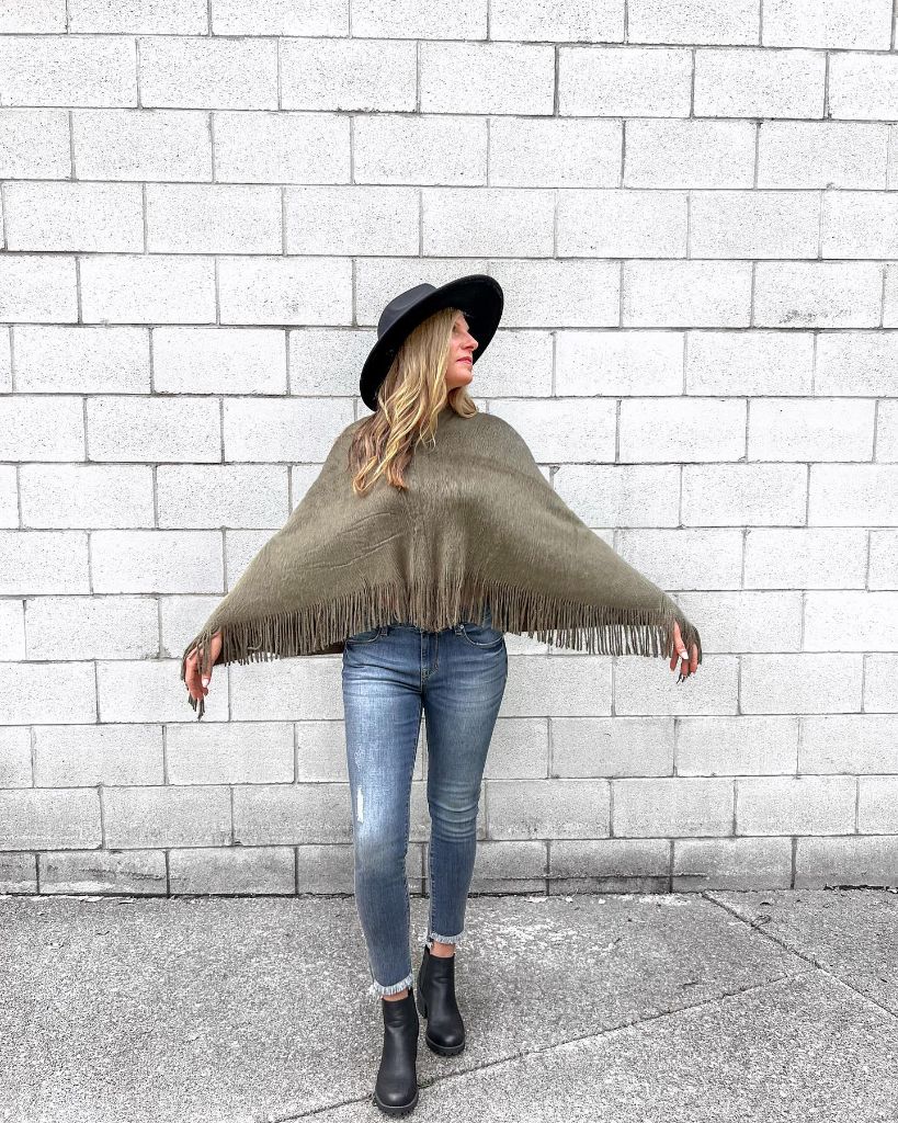 Olive fringed poncho with jeans and black hat