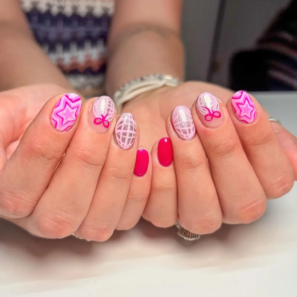 Pink star patterns and glitter lattice nail art on short oval nails August nails color 2026 ideas