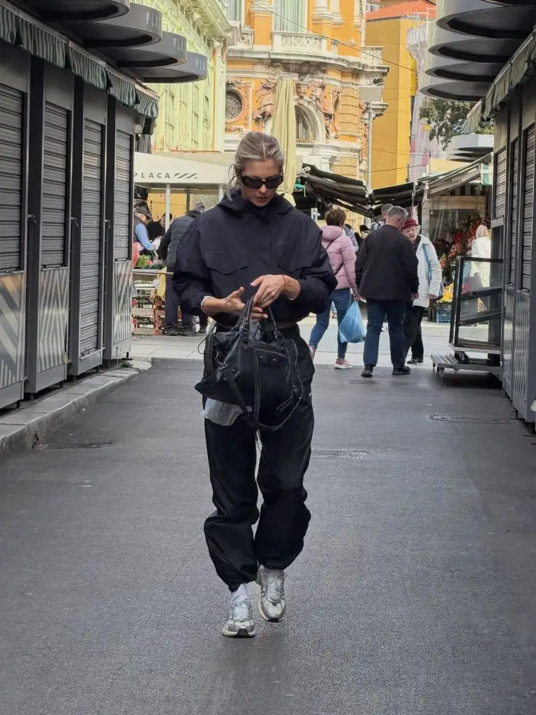 All-black utility outfit with cargo pants and silver sneakers at a European market