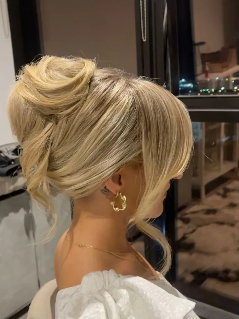 Fall Hairstyles for Wedding Guests 2026 Voluminous High Bun with Dramatic Curtain Bangs