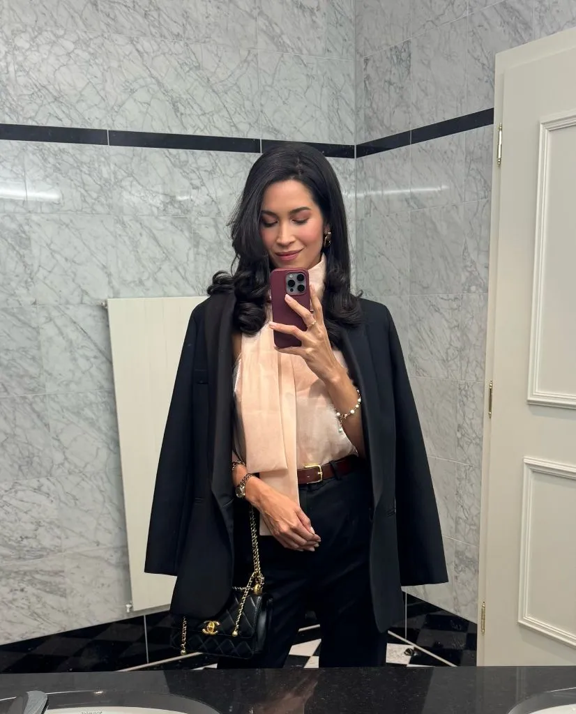 Blazer draped over shoulders with sheer blouse and Chanel bag