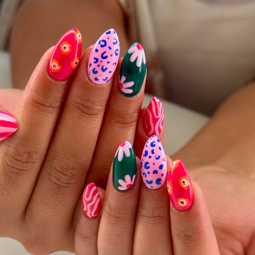 Bold mixed print nail art with leopard floral and swirl patterns on almond nails August nails color 2026 ideas