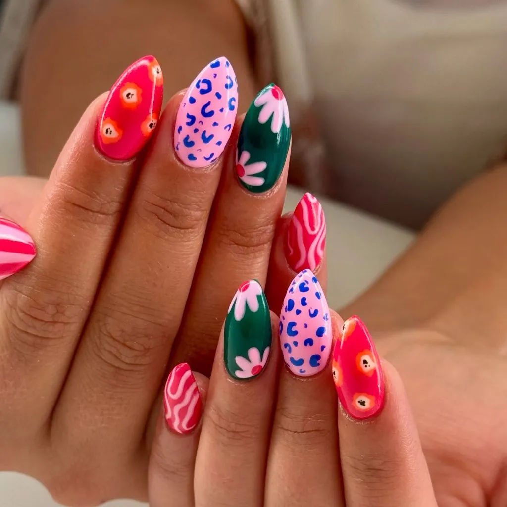 Bold mixed print nail art with leopard floral and swirl patterns on almond nails August nails color 2026 ideas