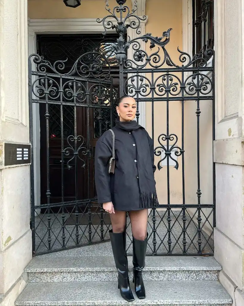 Black fringed cape coat with knee-high black boots