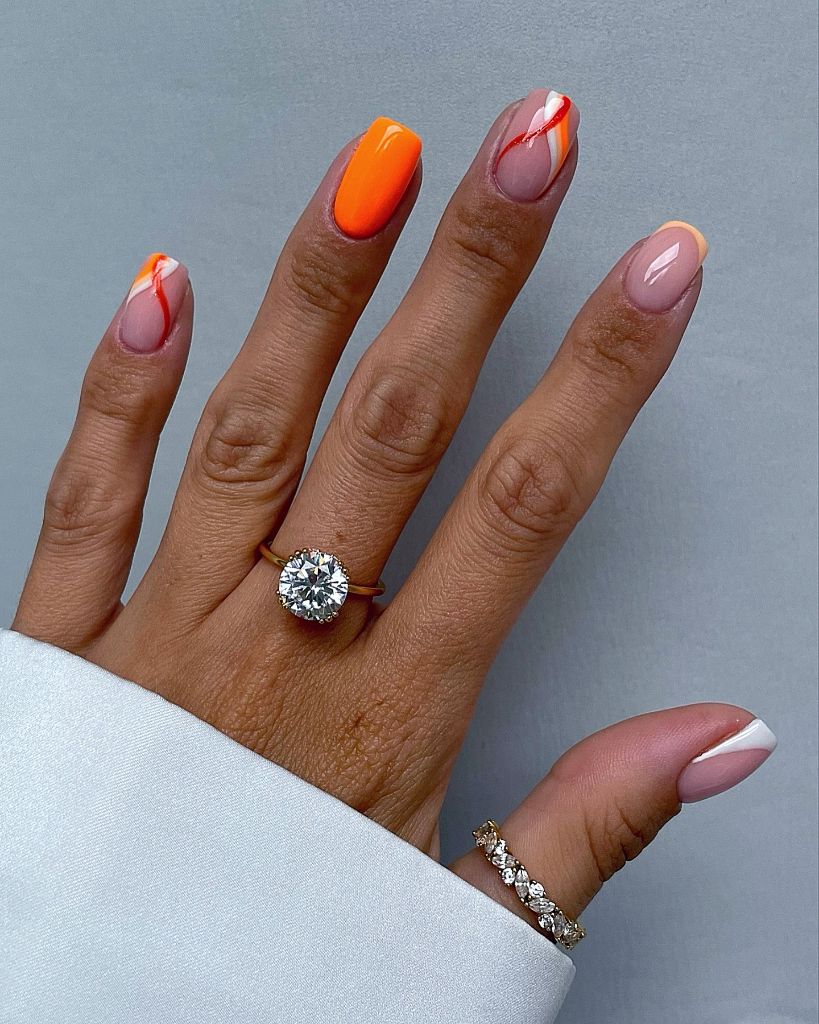 Bright tangerine orange nails with abstract swirl art and French tips, August nails 2026