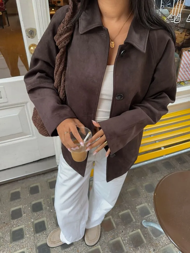 Dark brown suede jacket with white linen pants and woven bag