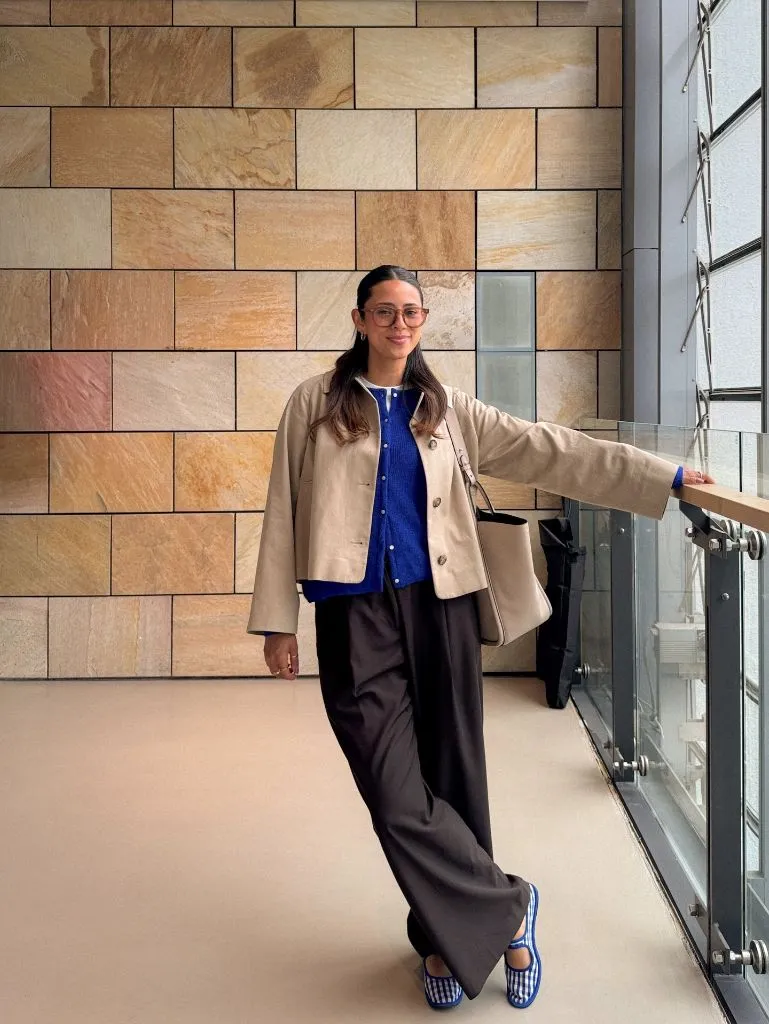 Beige boxy jacket over cobalt blue knit cardigan with dark wide-leg trousers and gingham shoes