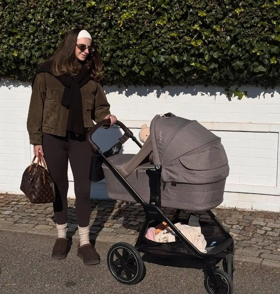 Mom with stroller wearing suede jacket and brown leggings