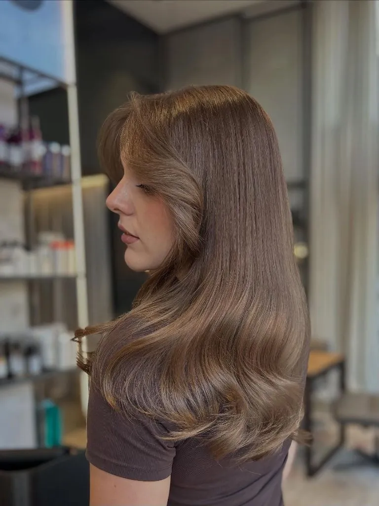 Side profile of glossy bronde hair with smooth voluminous curls