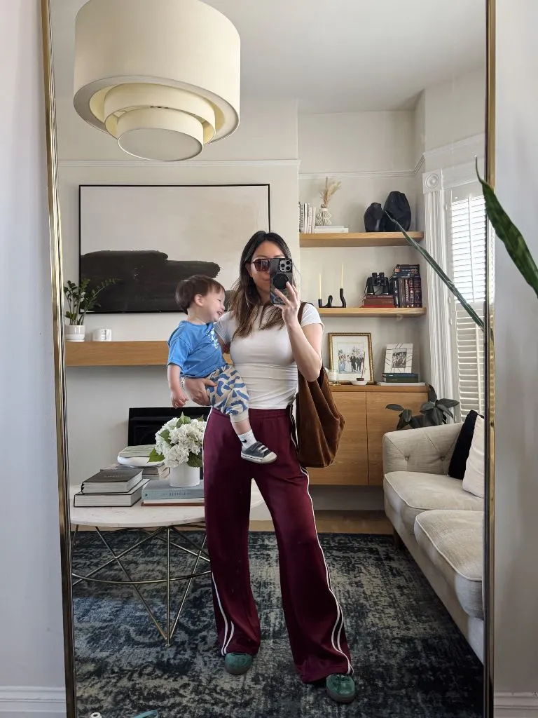 Mirror selfie with baby in white tee and burgundy track pants