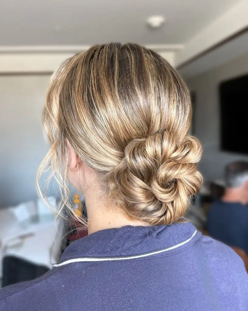 Fall Hairstyles for Wedding Guests 2026 Soft Looped Low Bun with Golden Highlights