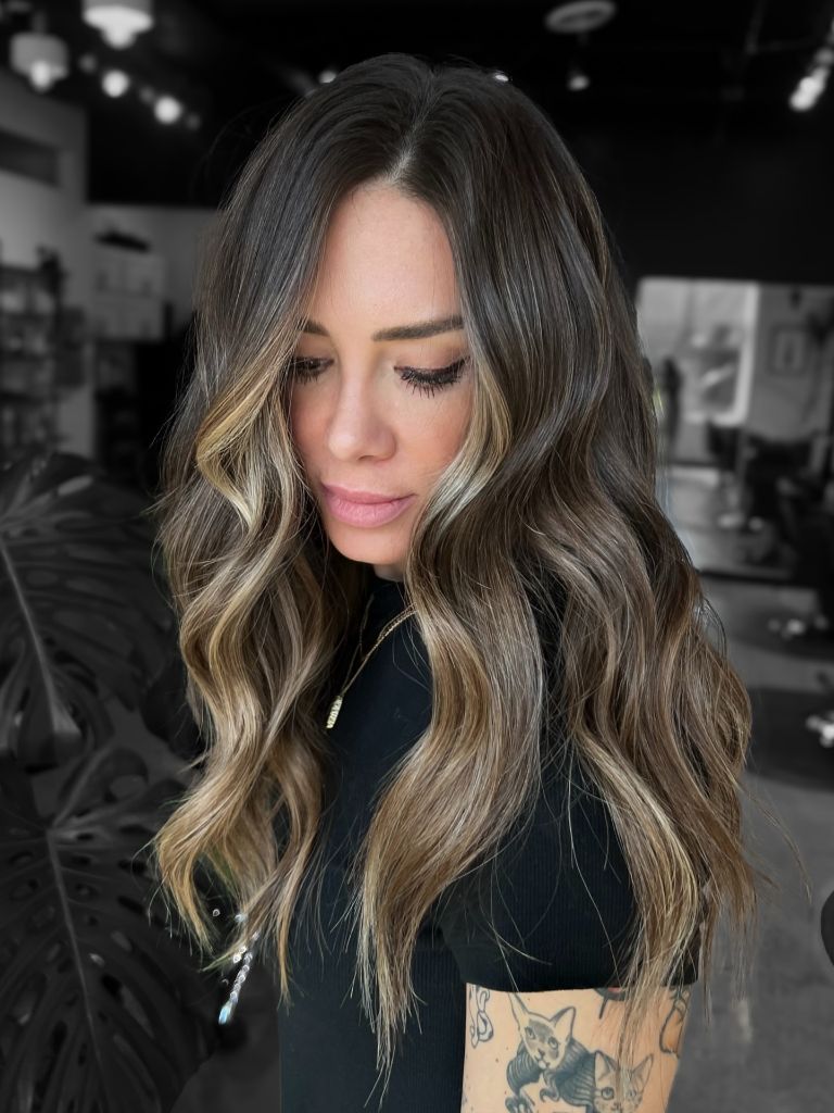 Dark brunette waves with a bold blonde money piece framing the face