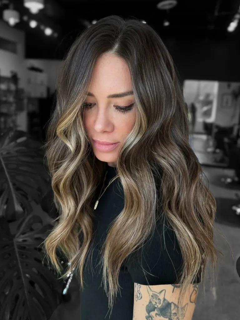 Dark brunette waves with a bold blonde money piece framing the face