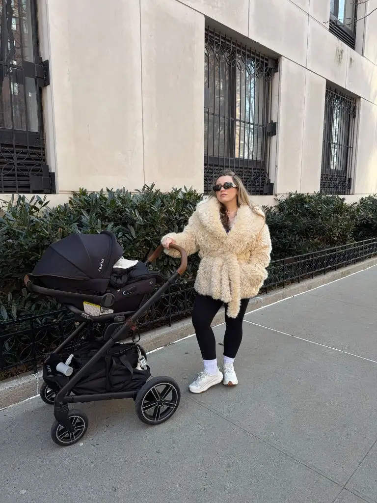 Mom with stroller wearing cream shearling coat and black leggings