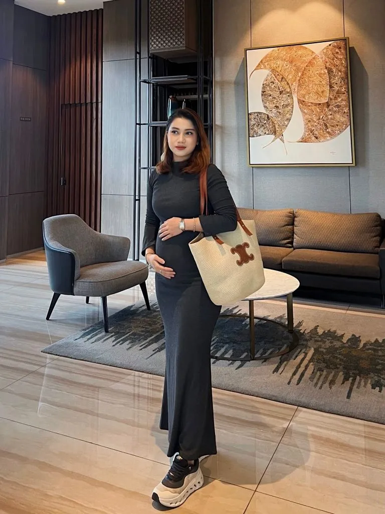Fall pregnancy outfit featuring a charcoal knit maxi dress with sneakers and a Celine straw tote