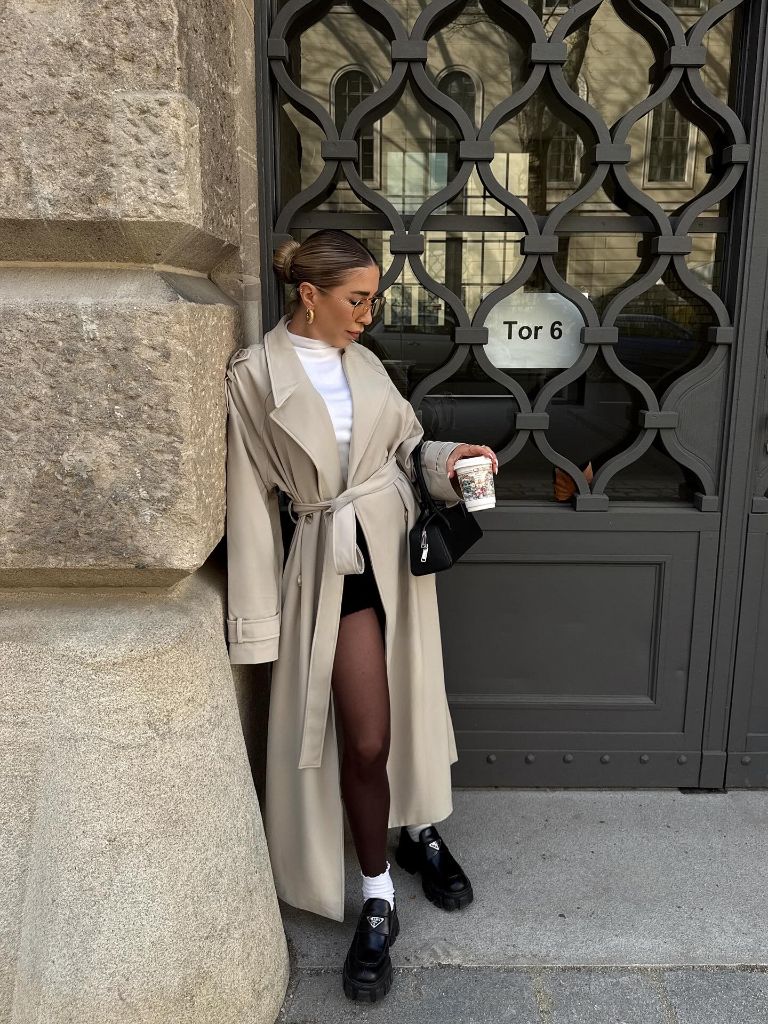 Beige belted trench coat with mini skirt and chunky Prada boots