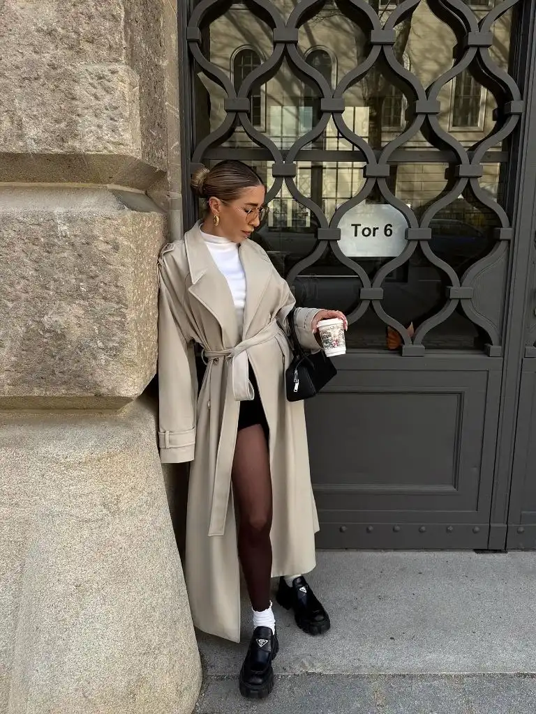 Beige belted trench coat with mini skirt and chunky Prada boots