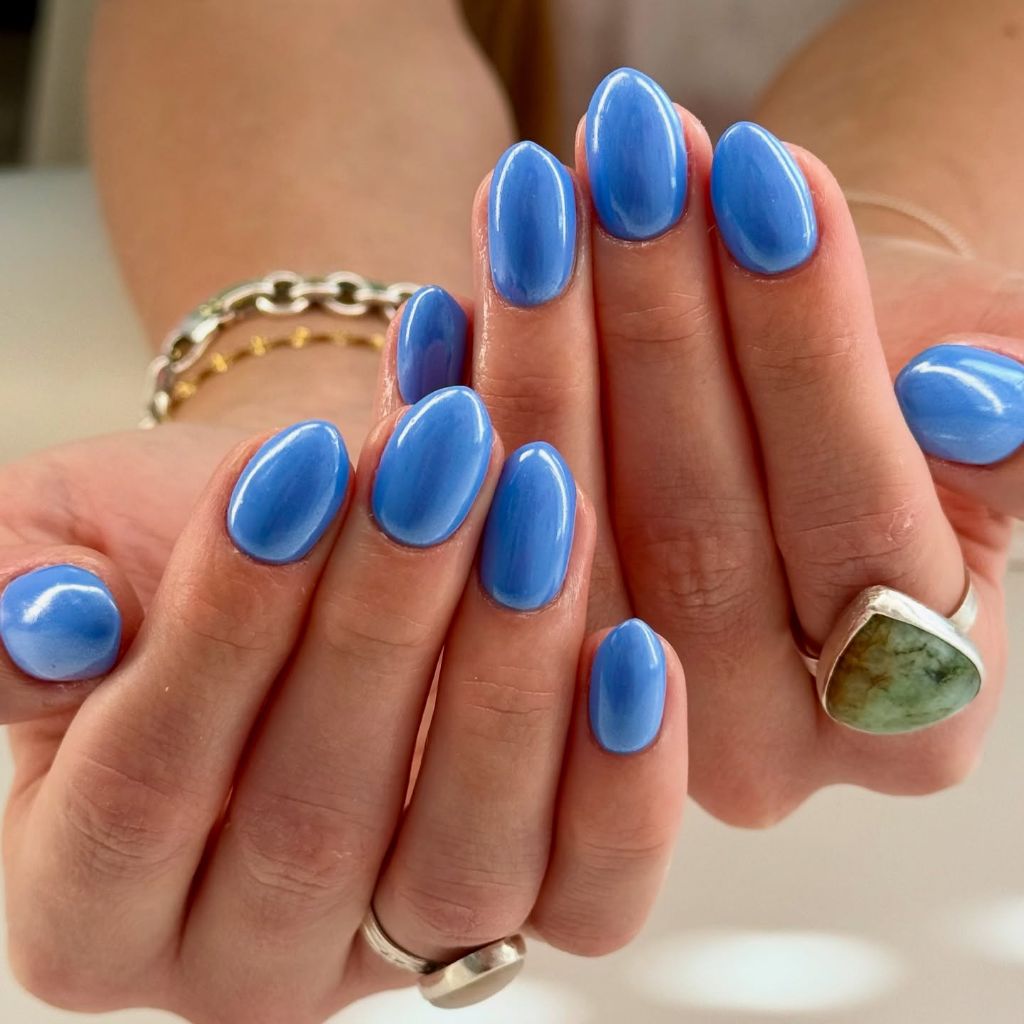 Solid cornflower blue glossy almond nails, simple August nails idea 2026