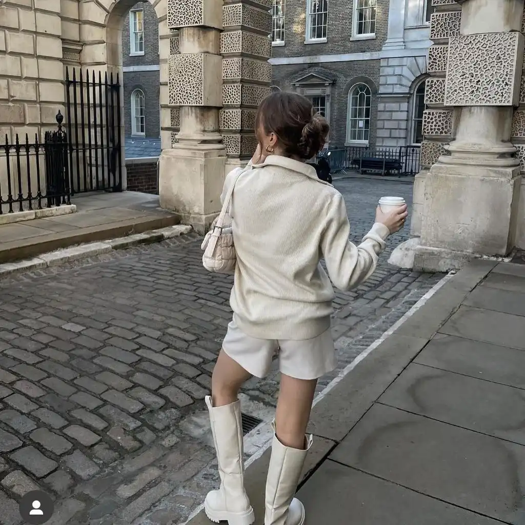 All-cream outfit with knit polo sweater, matching shorts, knee-high boots, and quilted cream bag in London courtyard