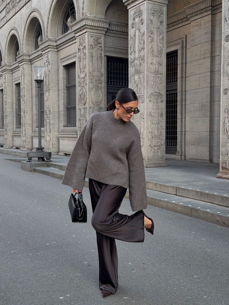 Grey oversized sweater with dark satin wide-leg trousers and black bag