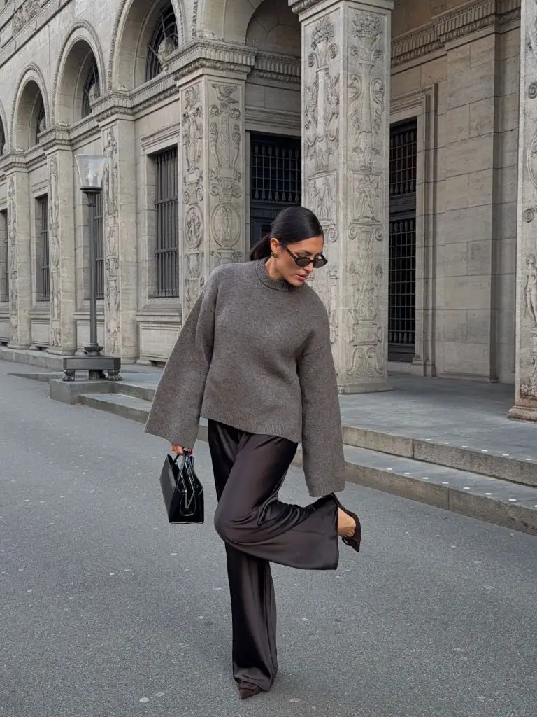 Grey oversized sweater with dark satin wide-leg trousers and black bag