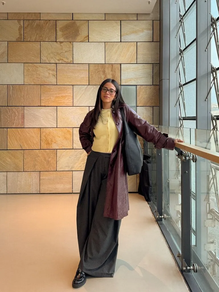 Burgundy leather coat over yellow sweater with dark wide-leg trousers