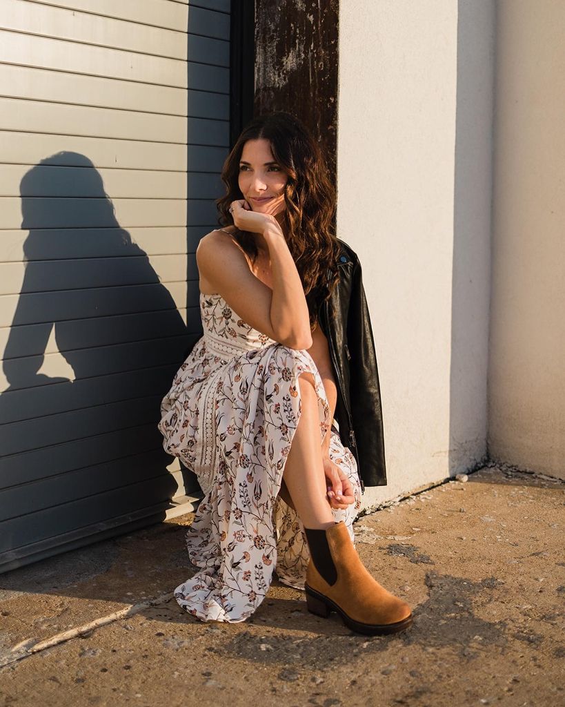 Floral maxi dress with leather jacket and Chelsea boots, seated pose