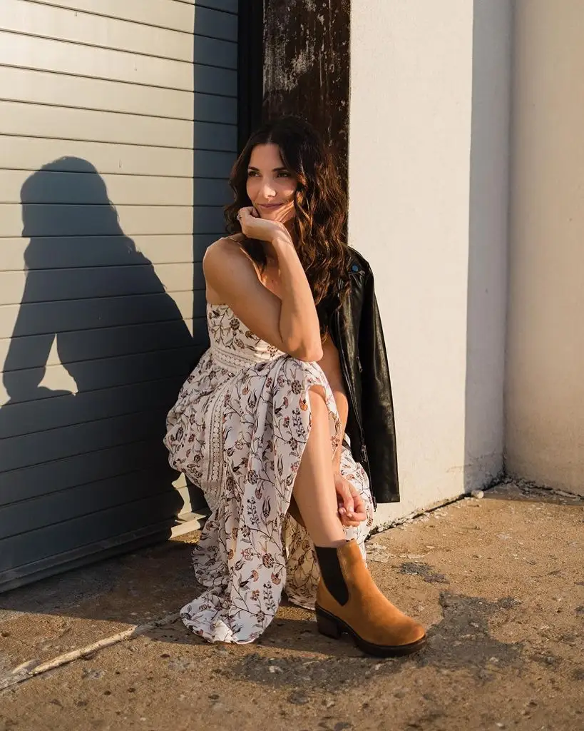 Floral maxi dress with leather jacket and Chelsea boots, seated pose