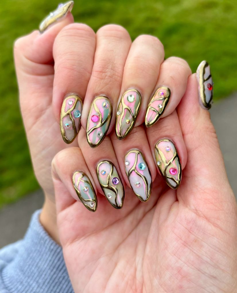 Stained glass nail design with gold outlines and colorful gems, August nails inspiration 2026