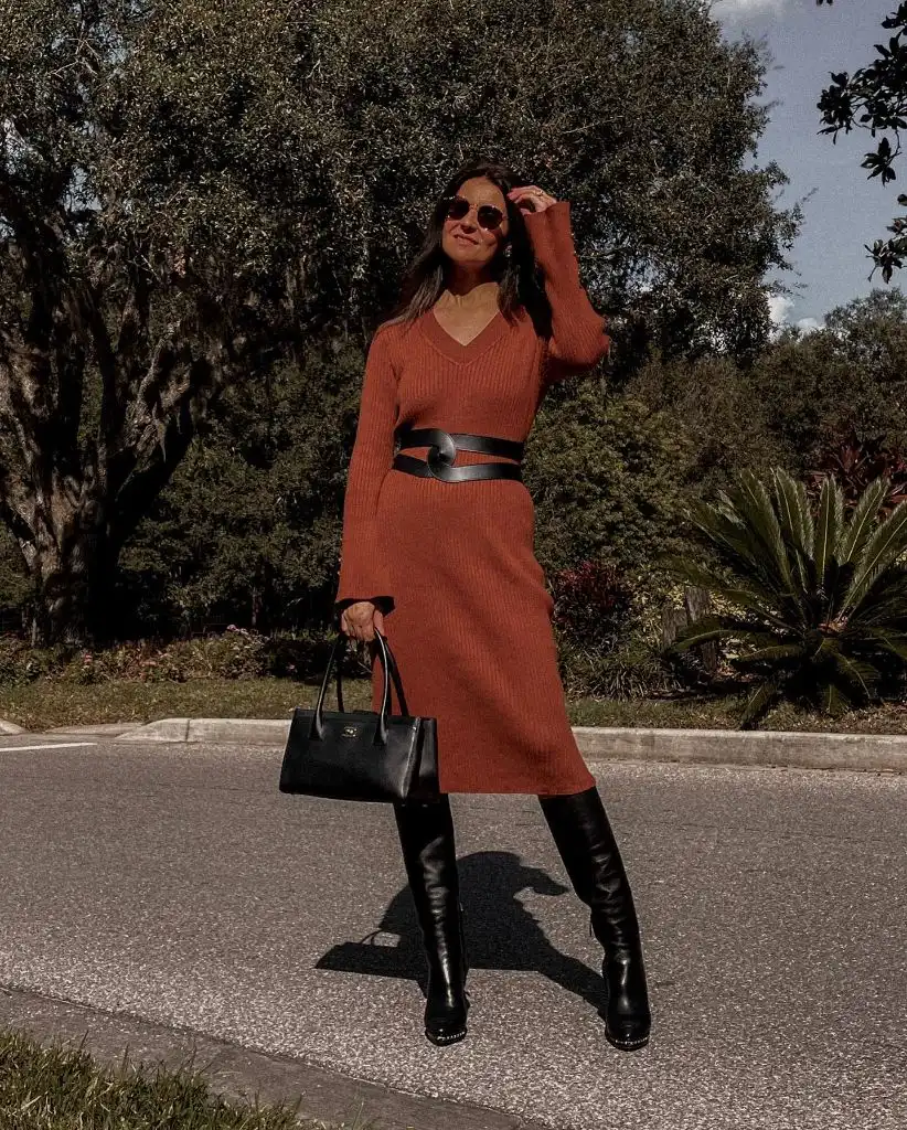 Rust ribbed V-neck sweater dress with black belt and tall black boots