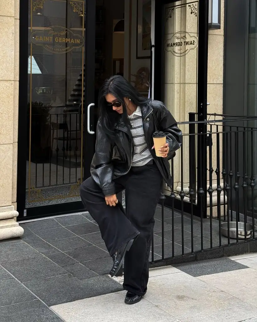 Black leather jacket over striped sweater with wide-leg black jeans