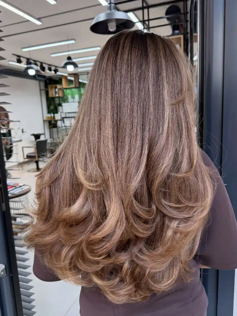 Long layered caramel brown hair with bouncy blowout from behind