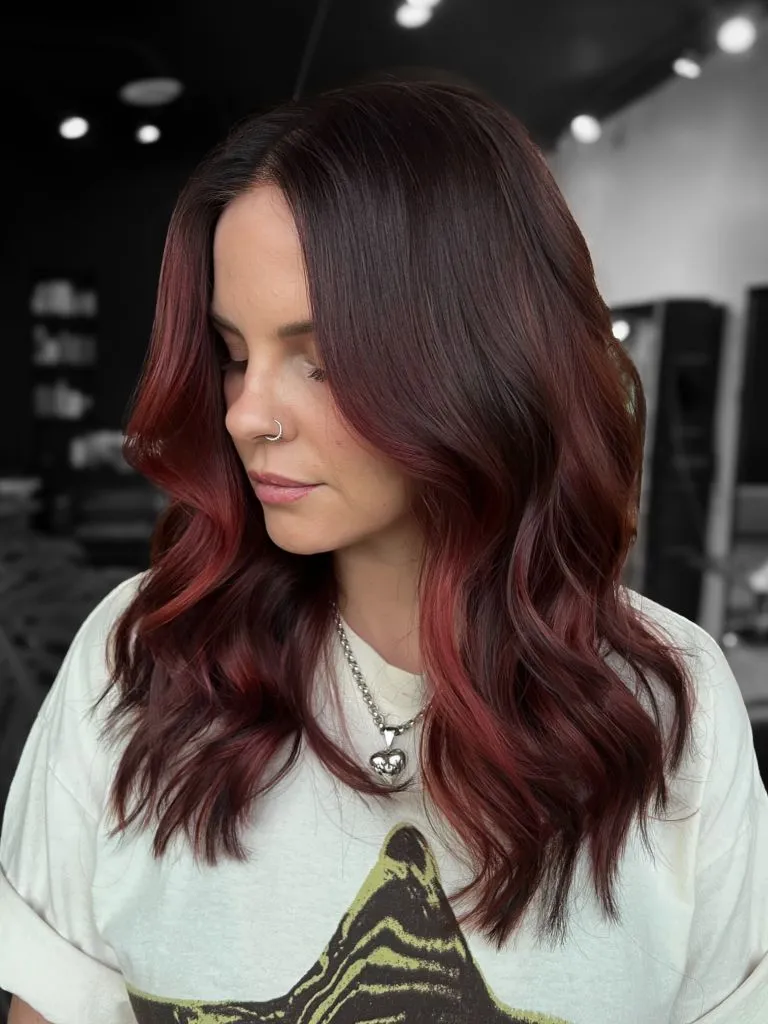 Dark brunette with soft cherry-red balayage through the waves
