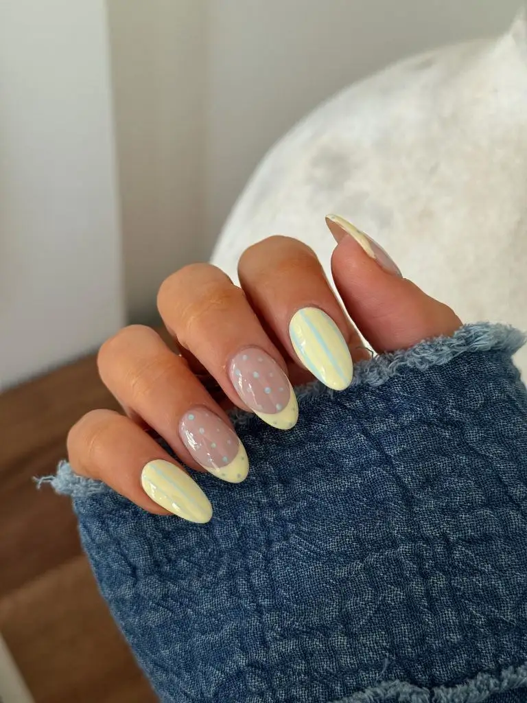 Pastel yellow and baby blue polka dot and stripe nails on almond nails August nails color 2026 ideas