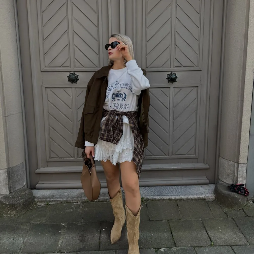 Graphic sweatshirt with eyelet skirt, plaid flannel, army jacket, and suede cowboy boots
