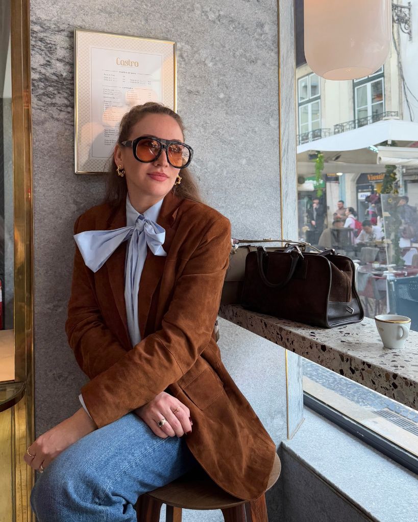 Brown suede blazer over blue pussy-bow blouse at European café