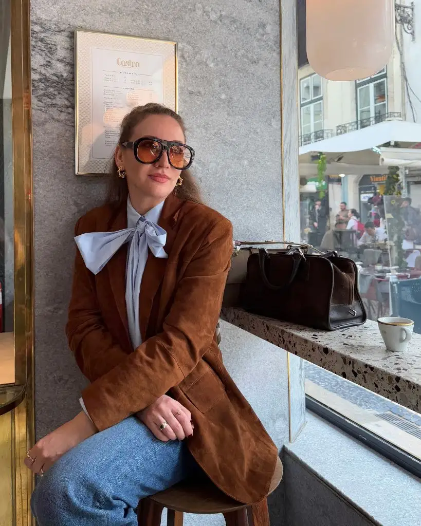 Brown suede blazer over blue pussy-bow blouse at European café