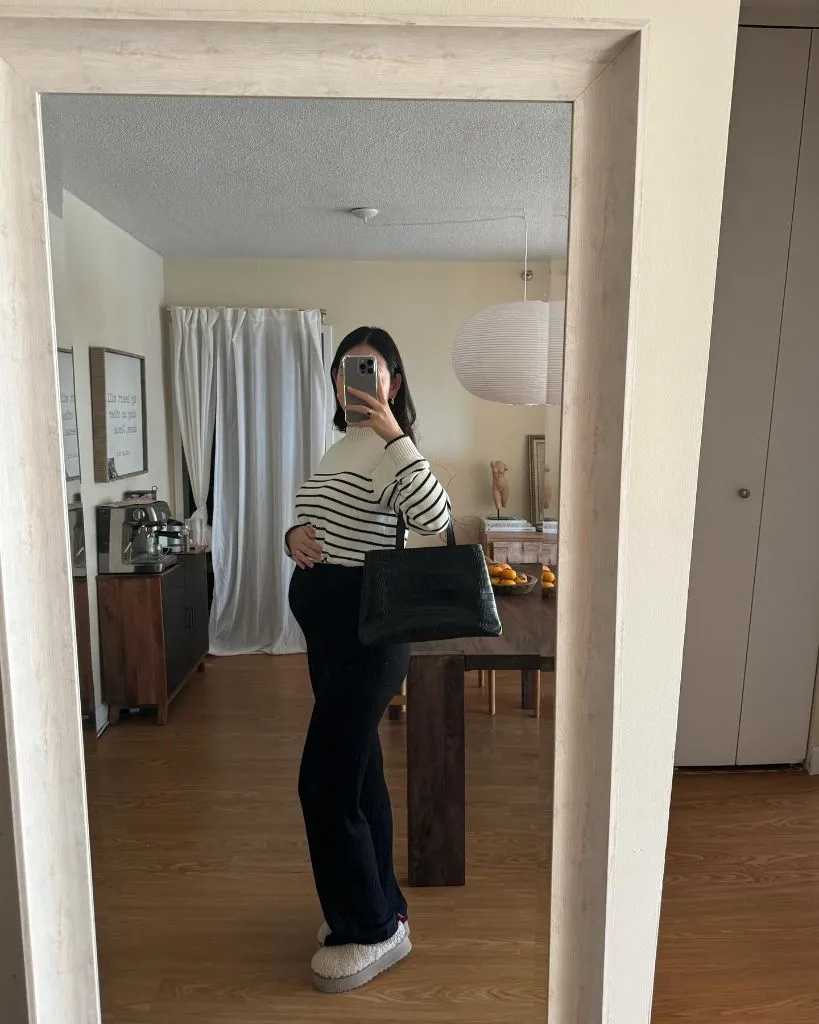 Mirror selfie pregnancy outfit with striped sweater, black wide-leg pants, and black croc bag