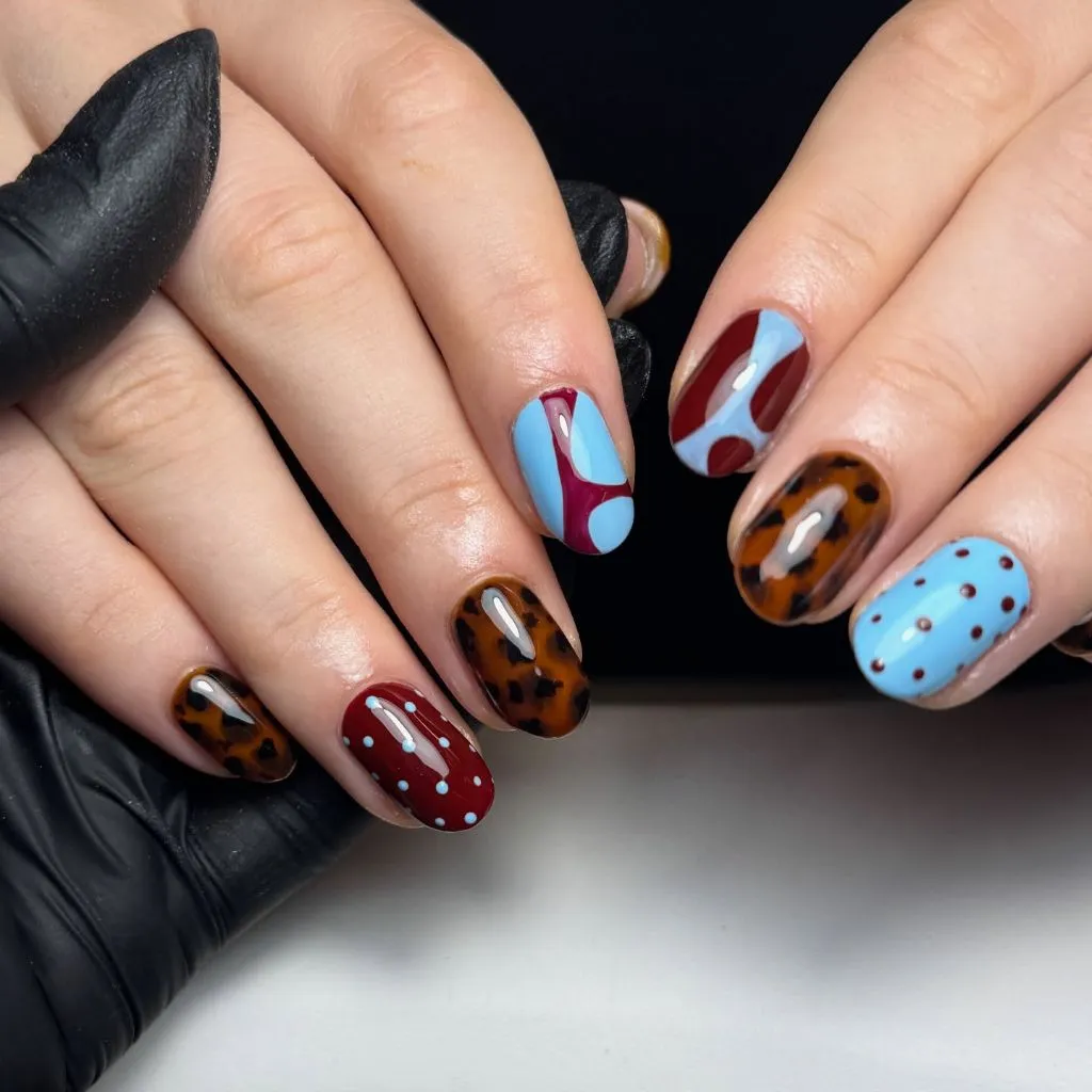 Eclectic mixed nail design with tortoiseshell, blue, and burgundy, bold August nails 2026