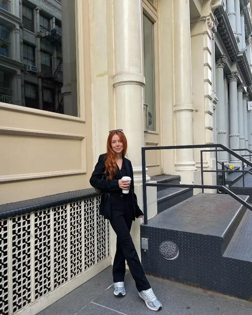 All-black outfit with black blazer, black trousers, and grey New Balance sneakers