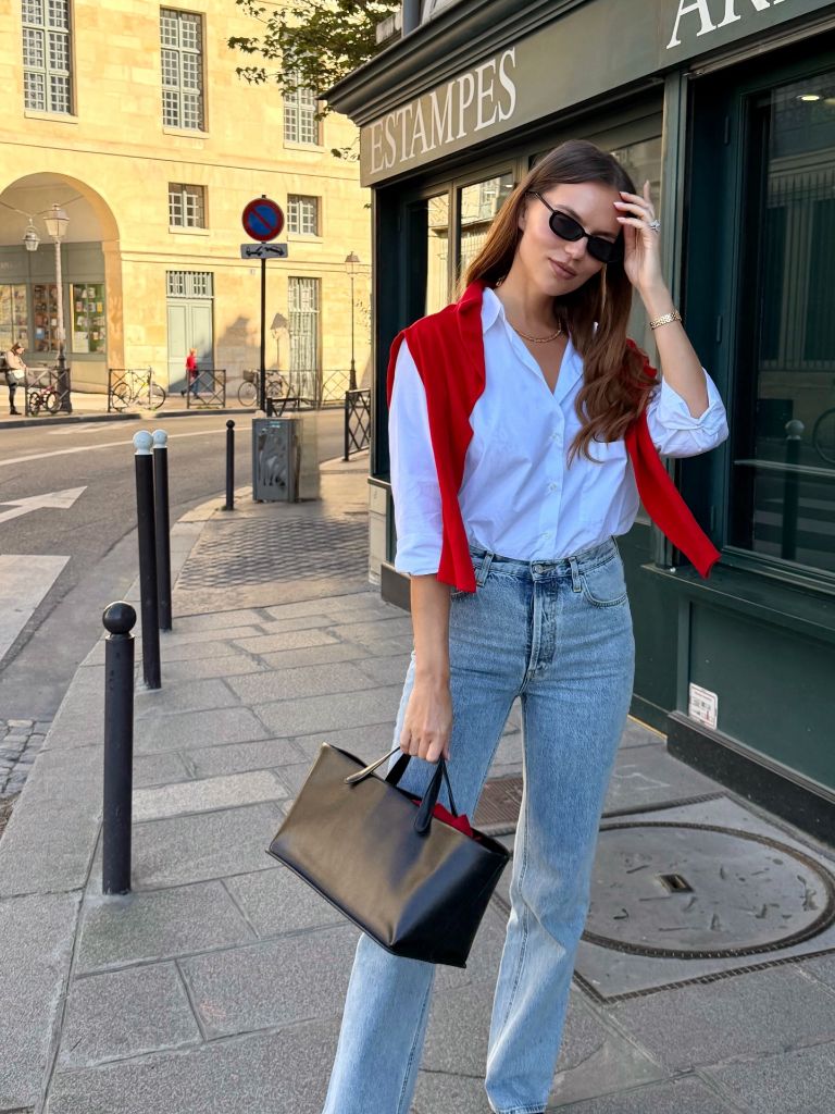 Fall professional outfit white button-down light jeans red sweater draped black bag
