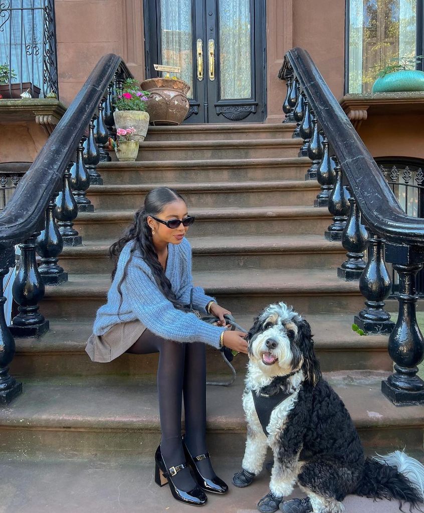 Blue oversized knit sweater with black tights and patent loafers sitting on NYC brownstone steps with a dog