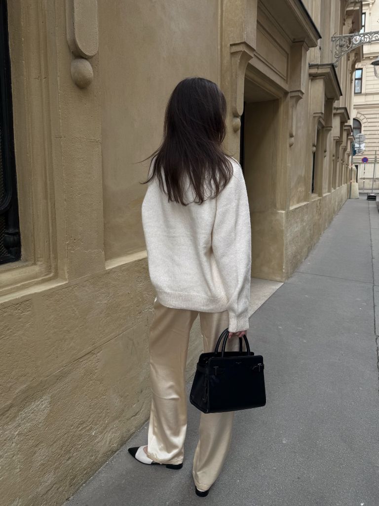 Rear view of cream knit and champagne satin trousers on European street