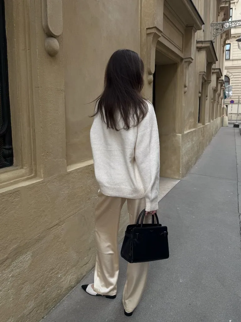 Rear view of cream knit and champagne satin trousers on European street