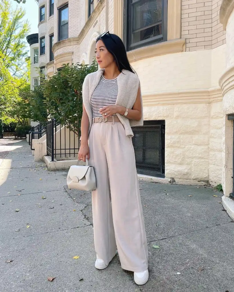 Black-and-white striped tee with beige knit sweater vest, blush wide-leg trousers, Dior belt, and cream bag