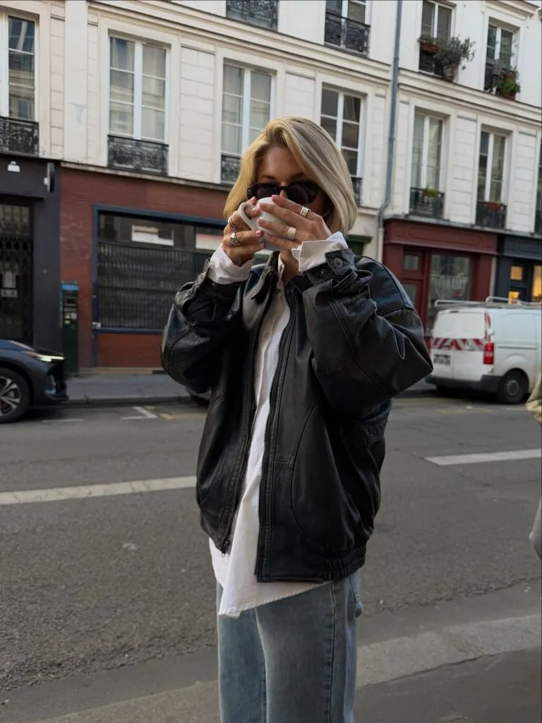 Black leather jacket with white tee and light jeans, drinking from cup