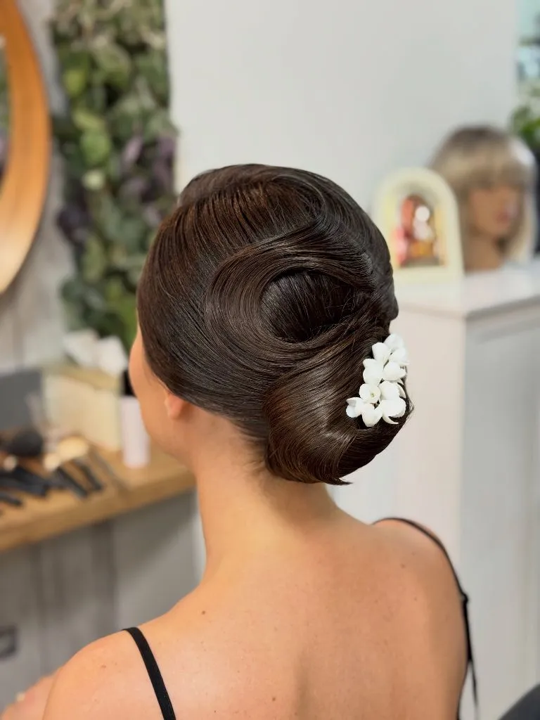 Fall Hairstyles for Wedding Guests 2026 Sculpted Vintage Chignon with Floral Accent