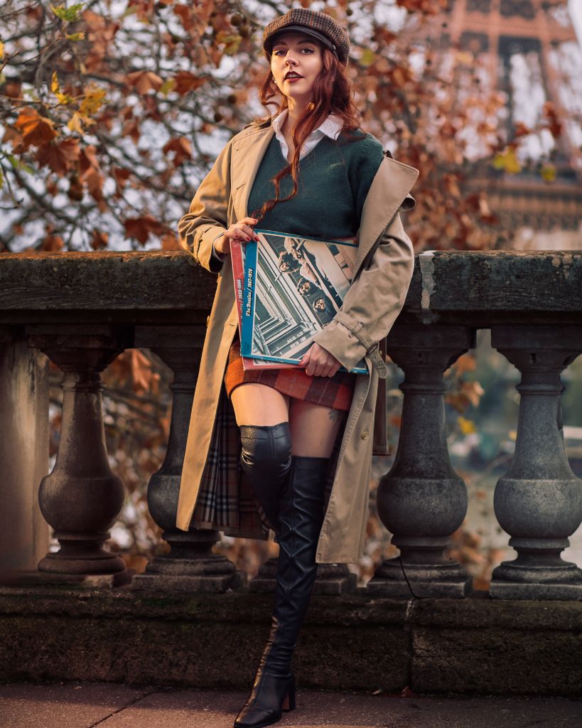 Beige trench coat with green sweater, plaid skirt, and black over-the-knee boots in Paris